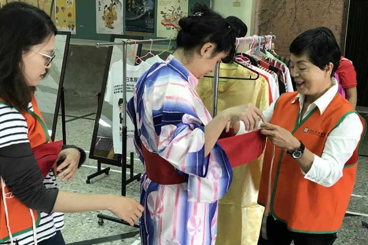 (2018-10-26、10-30)工作人員協助學童試穿體驗亞洲地區不同文化的傳統服飾。